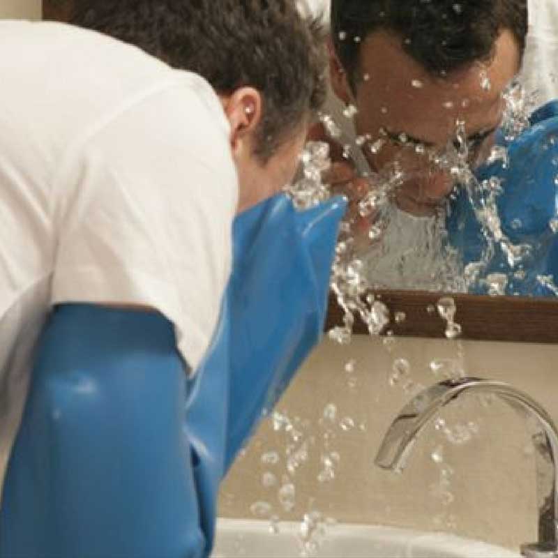 Man wearing waterproof arm cast protector while washing in the bathroom