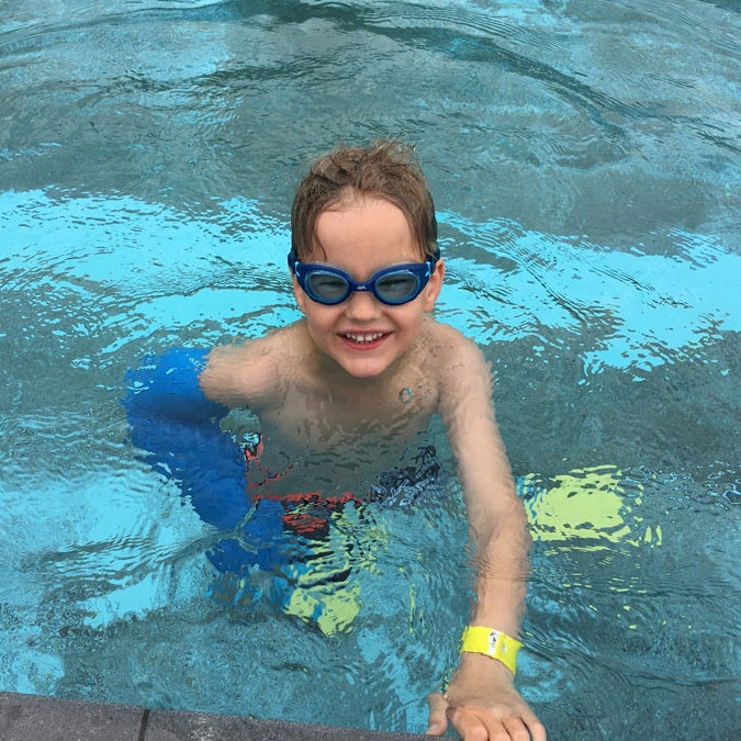 Young boy swimming with an arm cast cover