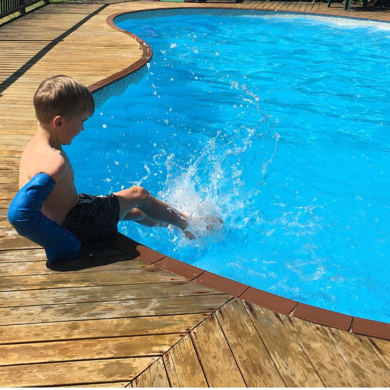 Beth's son sitting poolside with his waterproof full arm cover