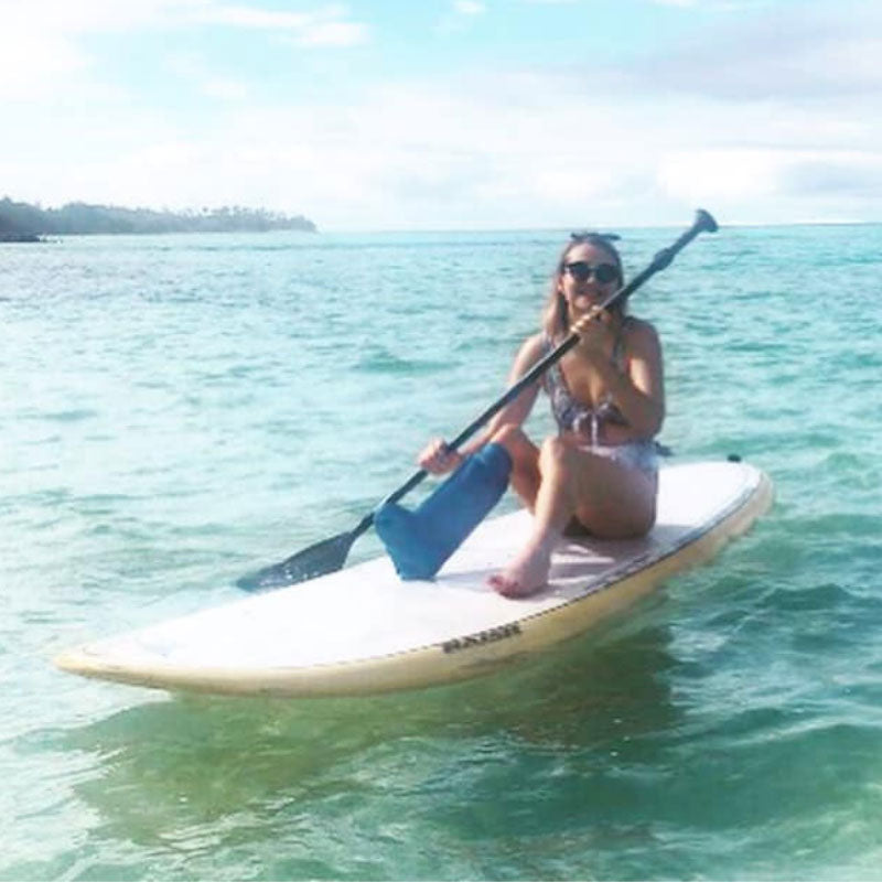 Jess on a stand up paddle board in Rarotonga wearing her bloccs short leg cast protector